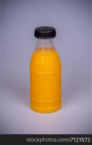 Orange juice in a plastic bottle on a gray background.