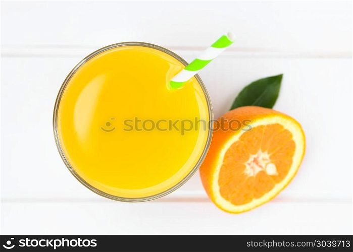 Orange juice in glass with drinking straw, photographed overhead on white wood (Selective Focus, Focus on the glass rim and the top of the juice) . Orange Juice