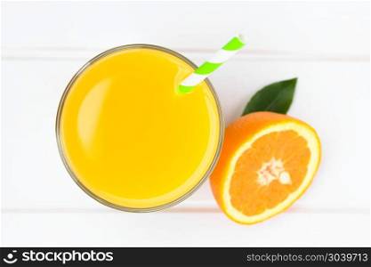 Orange juice in glass with drinking straw, photographed overhead on white wood (Selective Focus, Focus on the glass rim and the top of the juice) . Orange Juice