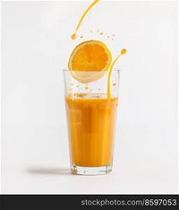 Orange juice in glass with orange slice and splashing liquid at white background. Healthy refreshing beverage with vitamins from citrus fruits. Front view.