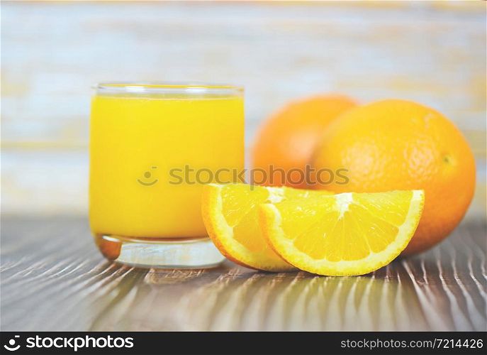 Orange juice in the glass and fresh orange fruit slice on wooden
