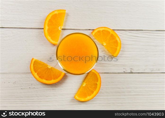 Orange juice in the glass and fresh orange fruit slice on wooden table