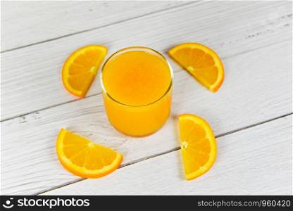 Orange juice in the glass and fresh orange fruit slice on wooden table
