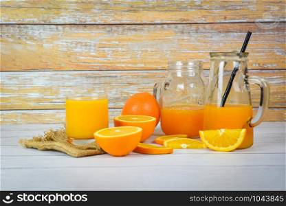 Orange juice in the glass jar and fresh orange fruit slice on wooden table / Still life glass juice on wood background
