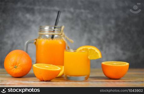 Orange juice in the glass jar and fresh orange fruit slice on wooden table / Still life glass juice on dark