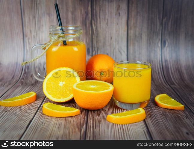 Orange juice in the glass jar and fresh orange fruit slice on wooden table / Still life glass juice on dark background