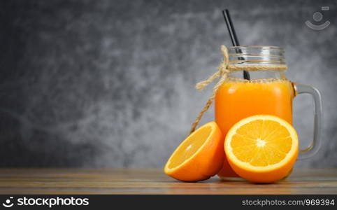 Orange juice in the glass jar and fresh orange fruit slice on wooden table / Still life glass juice on dark with copy space background