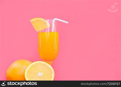Orange juice summer glass with piece orange fruit with red pink background