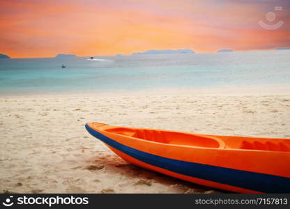 orange kayak boat on beach by blue sea under orange sky