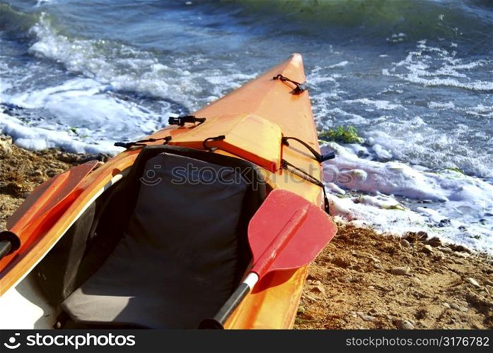 Orange kayak on a sandy shore of a river