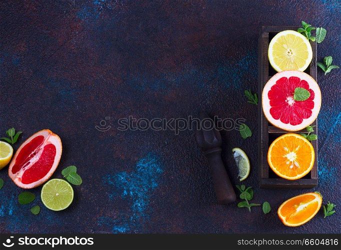 Orange, lemon and grapefruit with citrus reamer, copy space on dark background. Orange, lemon and grapefruit