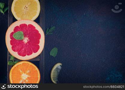 Orange, lemon and grapefruit with citrus reamer on dark background, retro toned. Orange, lemon and grapefruit