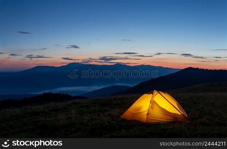 Orange luminous tent on the mountain in the evening or early morning. Orange luminous tent on the mountain in evening or early morning