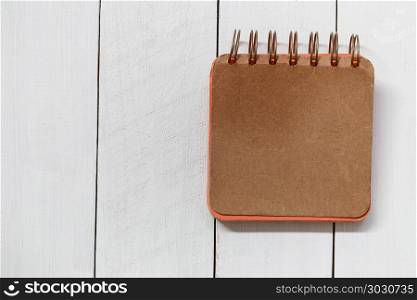 orange notebook placed on a white wooden floor.. orange notebook placed on a white wooden floor for design in your work.