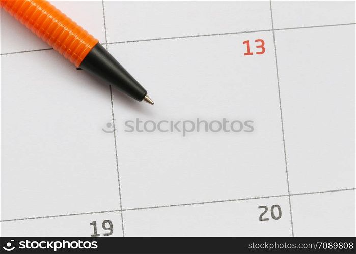 Orange pen is placed on the calendar in the 13th day and have copy space for design in your work concept.