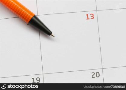 Orange pen is placed on the calendar in the 13th day and have copy space for design in your work concept.