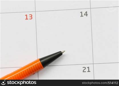 Orange pen is placed on the calendar in the 14th day and have copy space for design in your work concept.