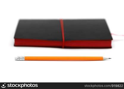 Orange pen on black leather moleskin notebook isolated on white. Orange pen with pink rubber on black leather moleskin notebook isolated on white