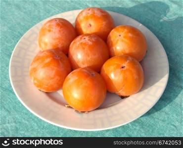 Orange persimmon fruits in a dish