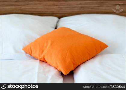 Orange pillow on a bed in a hotel room