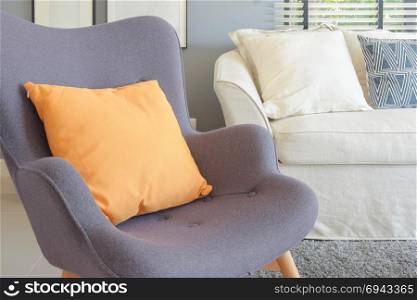 Orange pillow on retro style armchair in living room