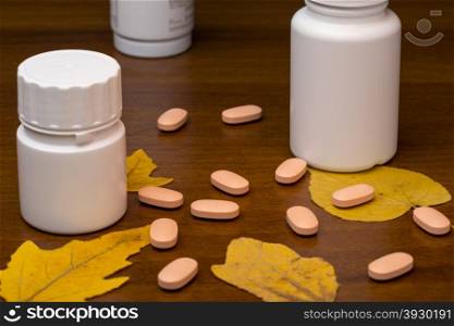 Orange pills and medicine bottle on wooden background. Orange pills and medicine bottle on wooden background with autumn leafs