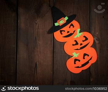 orange pumpkin felt figures on a brown background, Halloween festive backdrop