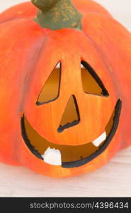 Orange pumpkin lantern with a spooky face smiling on a wooden grey background