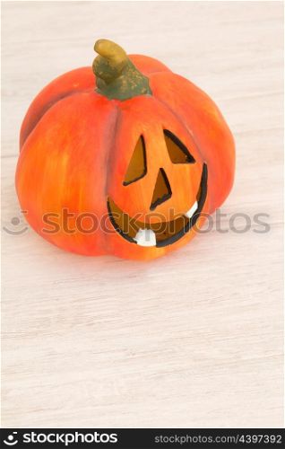 Orange pumpkin lantern with a spooky face smiling on a wooden grey background