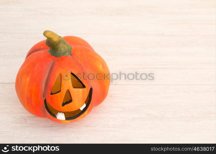 Orange pumpkin lantern with a spooky face smiling on a wooden grey background