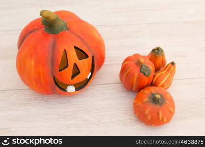 Orange pumpkin lantern with a spooky face smiling on a wooden grey background