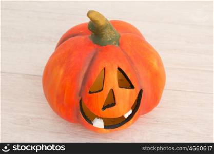 Orange pumpkin lantern with a spooky face smiling on a wooden grey background