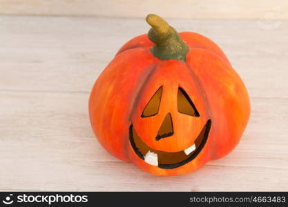 Orange pumpkin lantern with a spooky face smiling on a wooden grey background