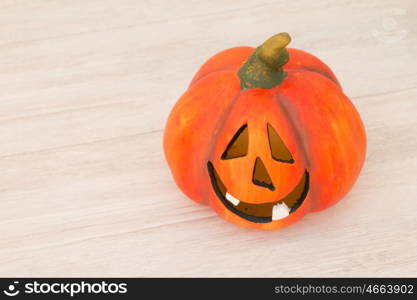 Orange pumpkin lantern with a spooky face smiling on a wooden grey background