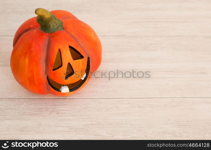 Orange pumpkin lantern with a spooky face smiling on a wooden grey background