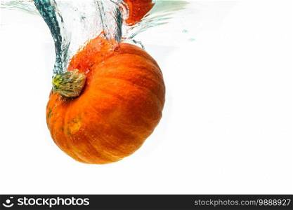 Orange pumpkin splashing into water isolated against white background. Healthy vegetables concept.. Orange pumpkin splashing into water isolated against white background.
