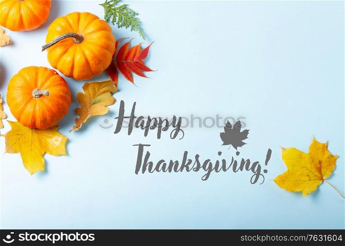 Orange pumpkins and leaves frame on blue backgroundwith happy thanksgiving greetings. pumpkin on table
