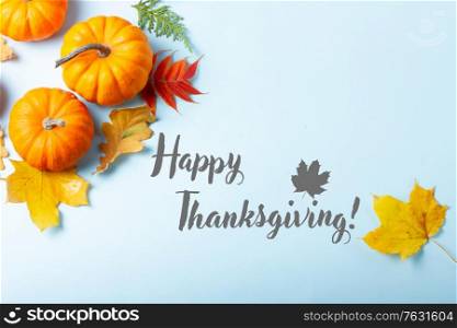 Orange pumpkins and leaves frame on blue backgroundwith happy thanksgiving greetings. pumpkin on table