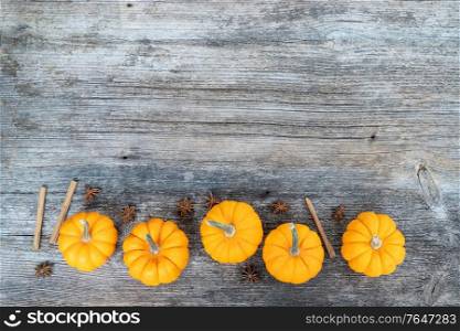 orange raw pumpkins and spices on old wooden textured table, top view border with copy space. pumpkin on table