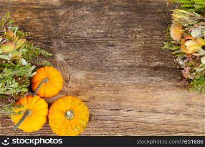 orange raw pumpkins with fall flowers on old wooden textured table, top view. pumpkin on table