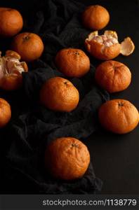 orange ripe mandarin on a black table, ripe and juicy fruits. Vegetarian healthy food, top view