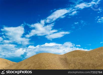Orange sand dunes against a beautiful blue cloudy sky.