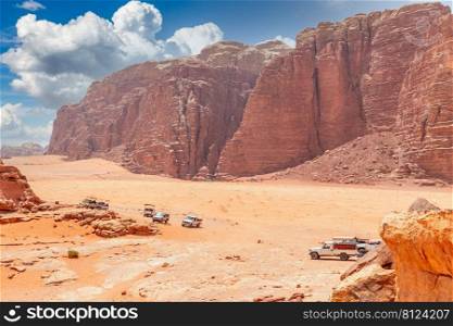 Orange sands and rocks of Wadi Rum desert with bedouin cars in the foreground, Jordan