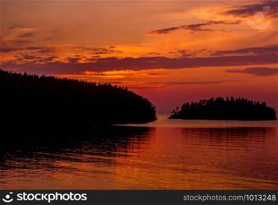 Orange sky at sunset and the water surface of the lake. Lake Ladoga at sunset