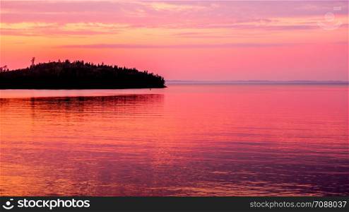 Orange sky at sunset and the water surface of the lake. Lake Ladoga at sunset