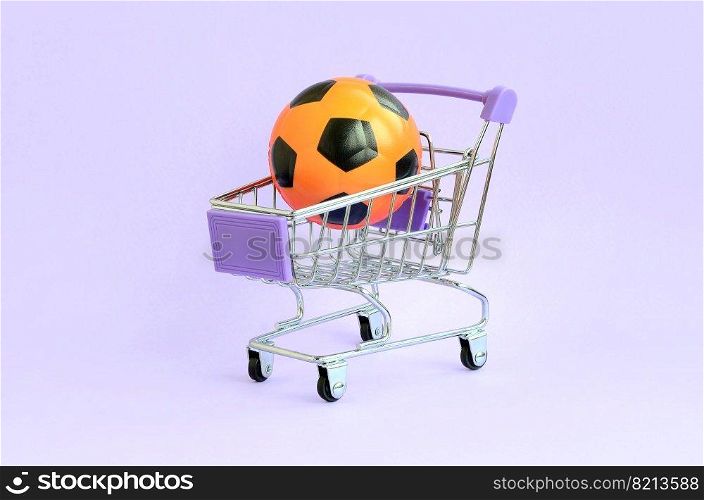 Orange soccer ball in shopping cart on violet. The concept of selling sports equipment, predictions for sports matches, sports betting. Selling sports equipment. predictions for matches. sports betting