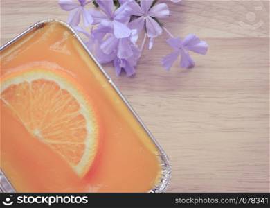 Orange soft cake with sliced orange fruit in aluminum foil tray on wooden background. Retro-Vintage filter effect