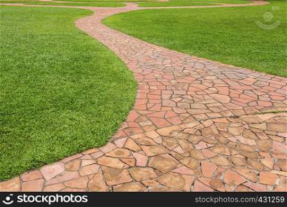 Orange stone walkway with green grass in park. Abstract background.