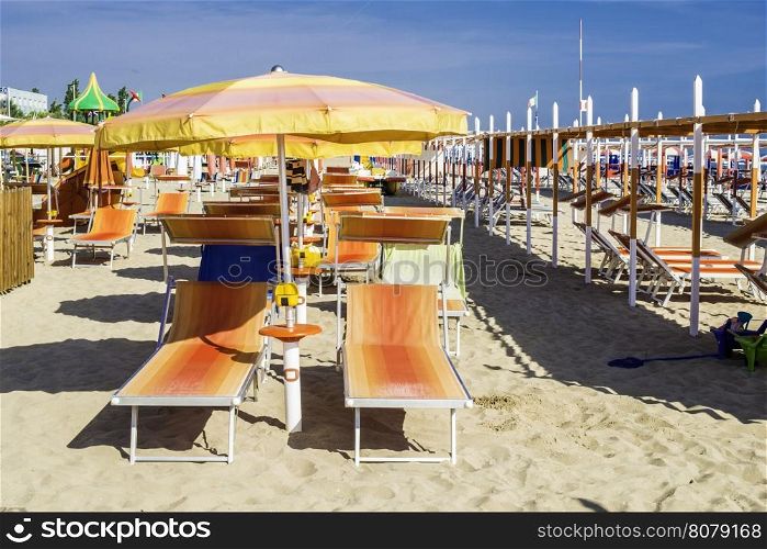 Orange sunbeds and umbrellas on the beach.