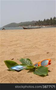 Orange sunglasses and bank cards lying on the sand beach. India Goa.. Orange sunglasses and bank cards lying on the sand beach. India Goa